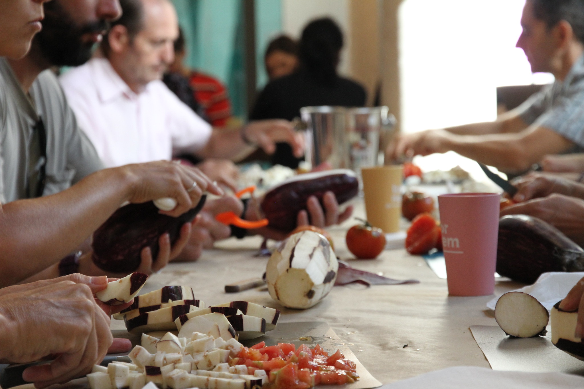 Imagen de los participantes en ToNoWaste en la mesa cortando berenjenas y tomates