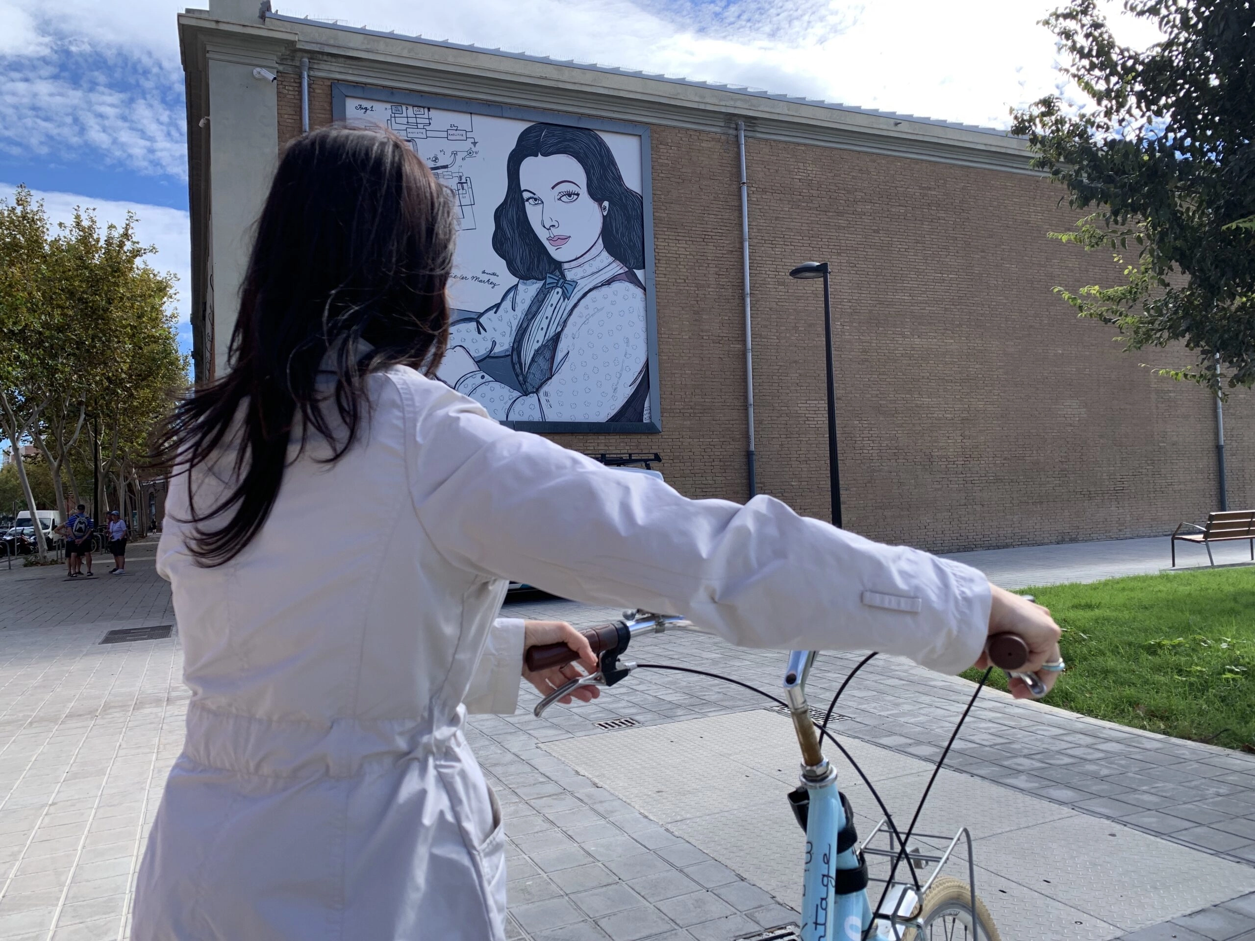 Fotografía de una participante de Pedaletjant amb Dones de Ciència ante un mural del itinerario