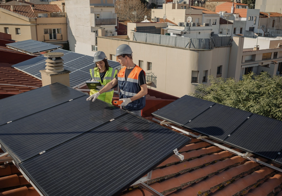 Fotografía de dos operarios en un tejado revisando placas fotovoltaicas